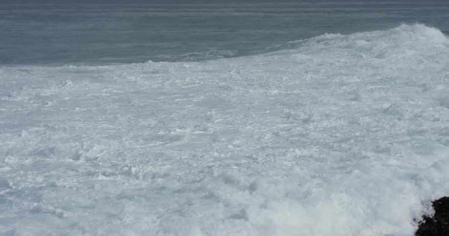 Rolling waves crash against a rocky shore