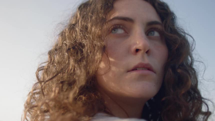 A young woman quickly turns her head and looks behind her