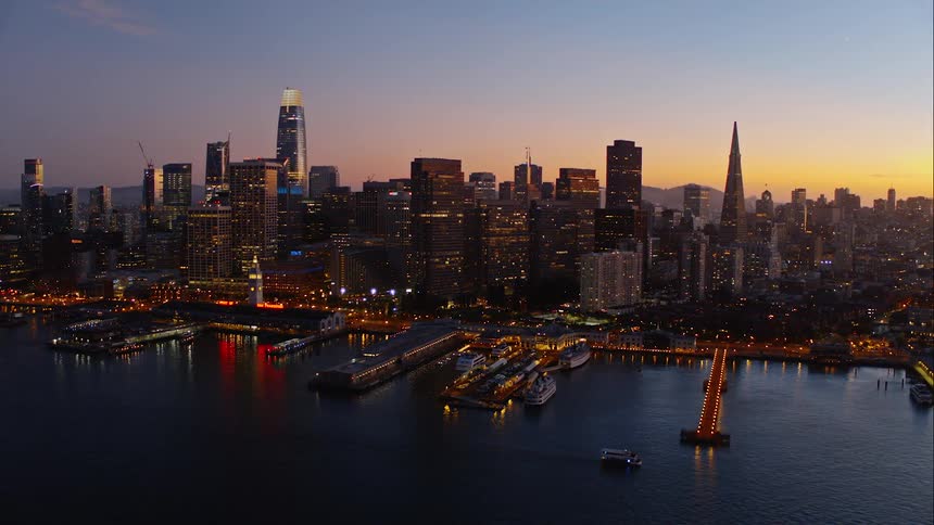 The picturesque skyline of downtown san francisco is filled with building lights as the sun sets over the city