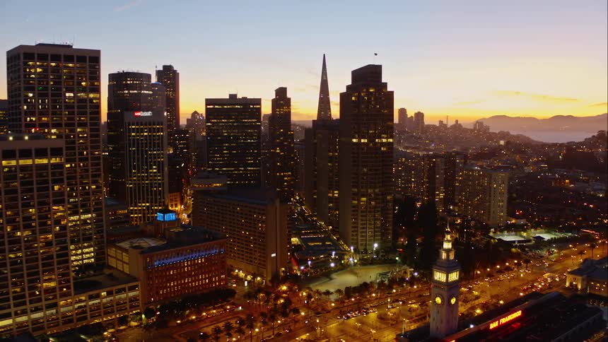 A busy urban location with tall buildings at sunset