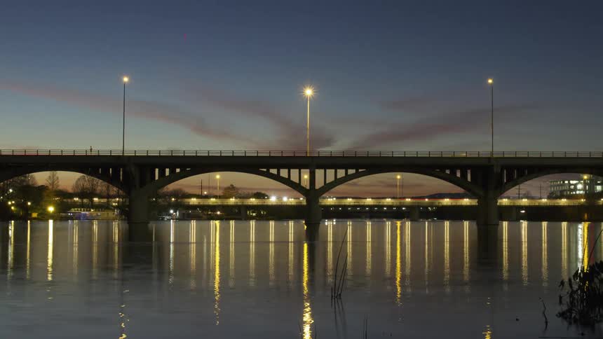 Vehicles cross a bridge at dusk