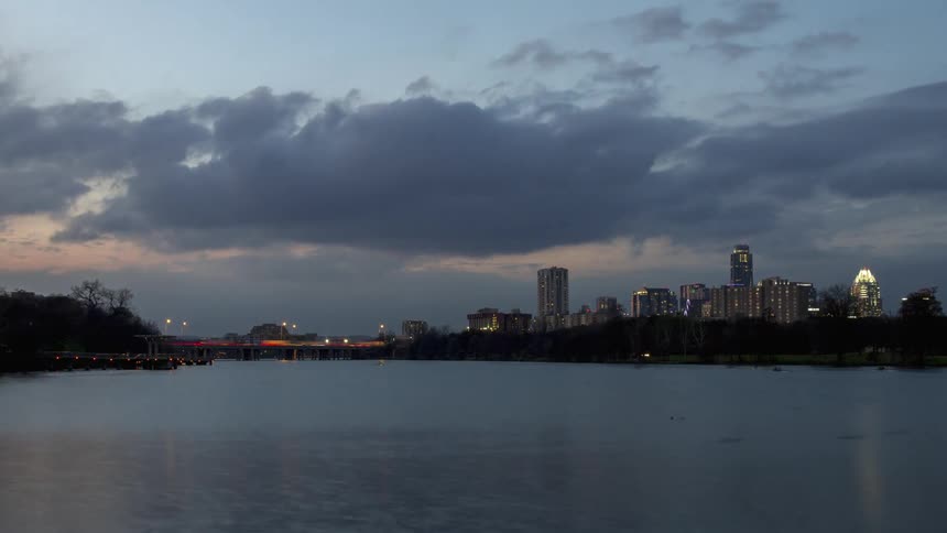 Clouds float over city buildings at dusk