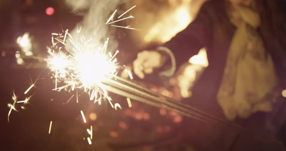 People gathered near a fire waving sparklers around