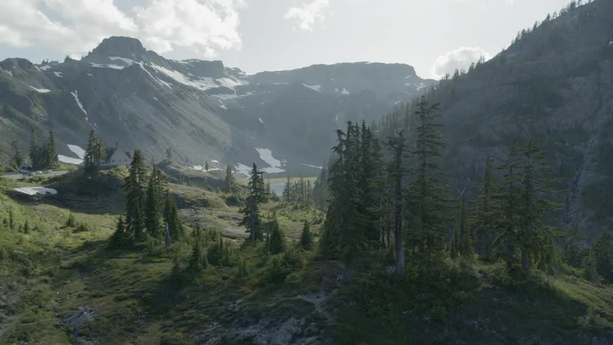 Mountain valley landscape with trees, lake, hiking paths and lodge in the distance