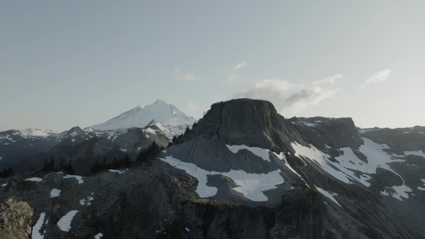 Snow capped mountain top reveal under blue skies