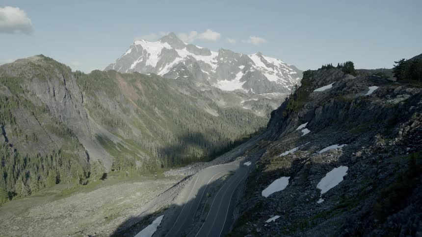 Revealing a winding mountain road with hairpin curve along a rocky ridge above a deep valley