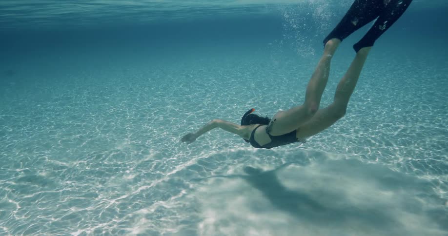 A woman swims in shallow open waters while wearing a snorkel and flippers