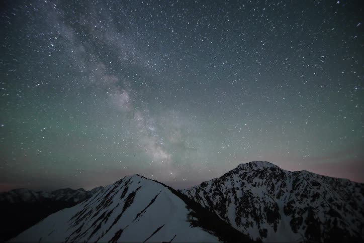 Stars move across the sky above snowcapped mountains