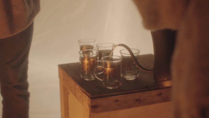 Person pours brew into mugs from pot