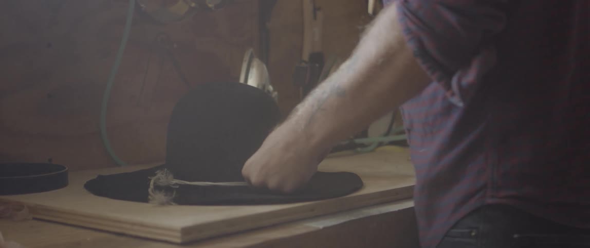Man adds hat band to wide brim hat