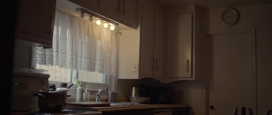 A kitchen with white cabinets walls and appliances with burnt out bulbs over the sink