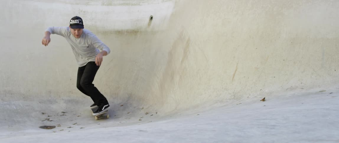 A man skateboards in an empty swimming pool