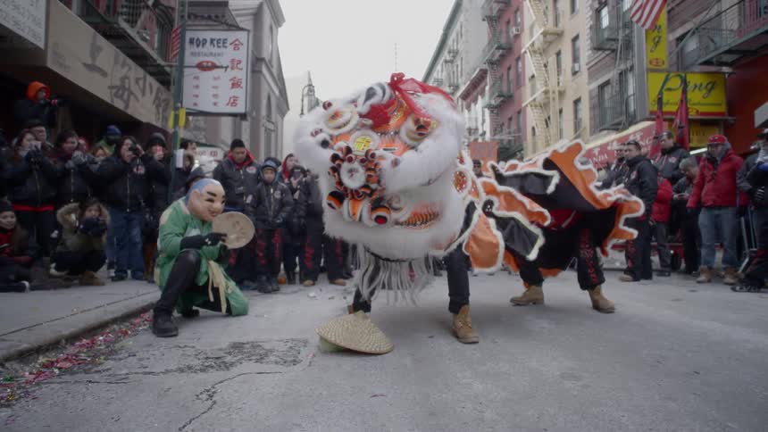 A lion costume dances on the street