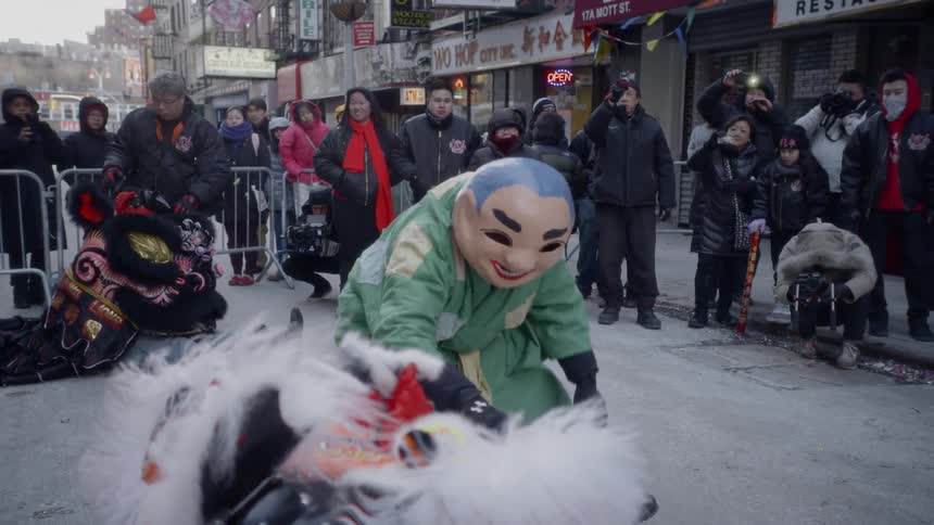 A man in a traditional chinese costume approaches another performer in a dragon costume