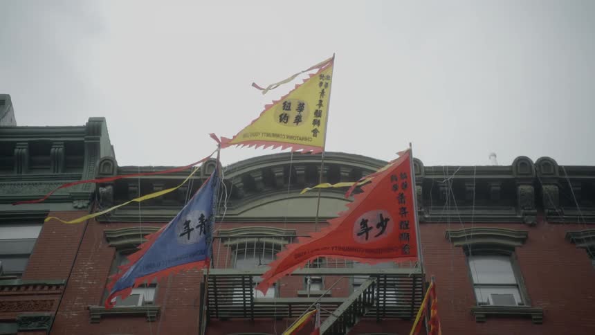 Flags on poles in front of a building flutter in the breeze