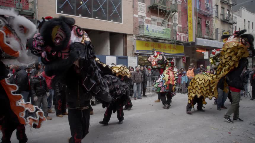 People are gathered and watching a chinese dragon dance on a city street