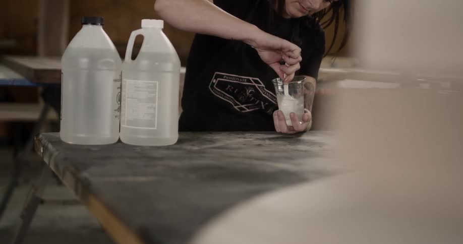 Woman mixing chemicals to make transparent resin on a plastic cup