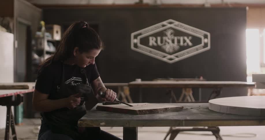 A woman uses a mallet and a chisel to carve a piece of stone