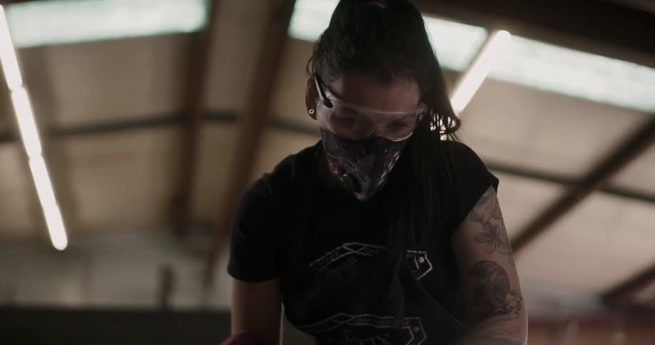 A woman wears a mask while using a tool