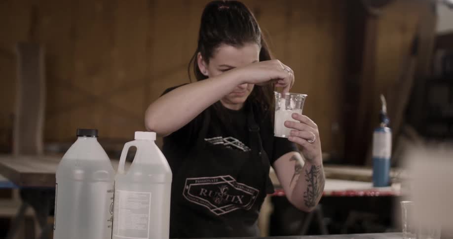 A woman stirs something in a cup