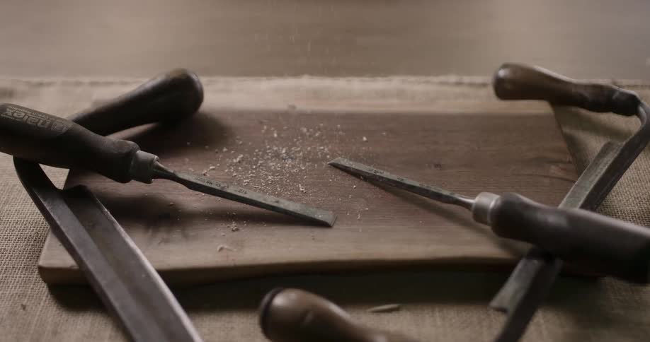 Sawdust falling on carpenter tools laying on piece of wood