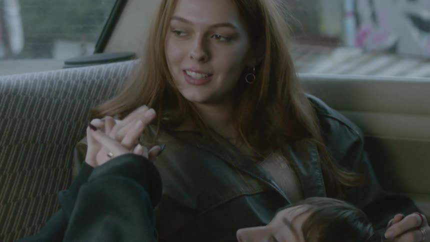 Lesbian couple relaxing in a car holding hands and talking