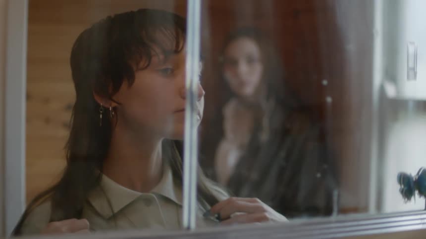 A teenage girl looks into a mirror while she fixes her hair