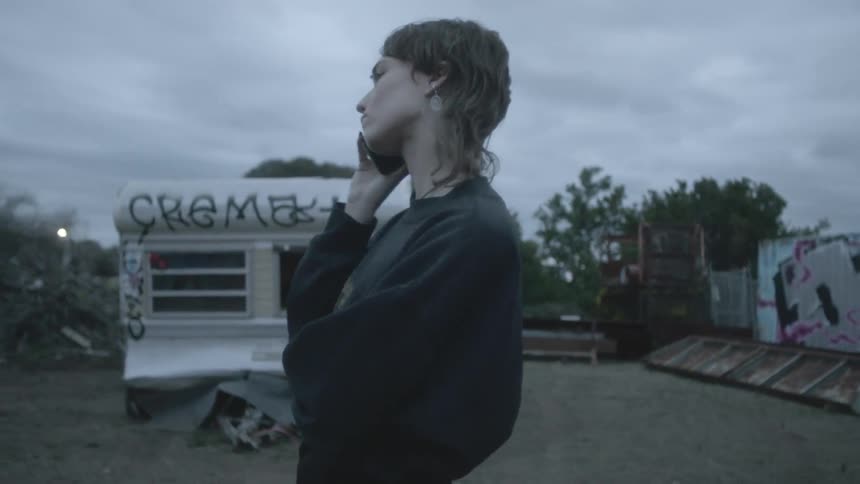 Woman speaks by mobile phone in the junkyard on a cloudy day