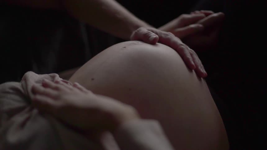 A man holds the stomach of a pregnant woman