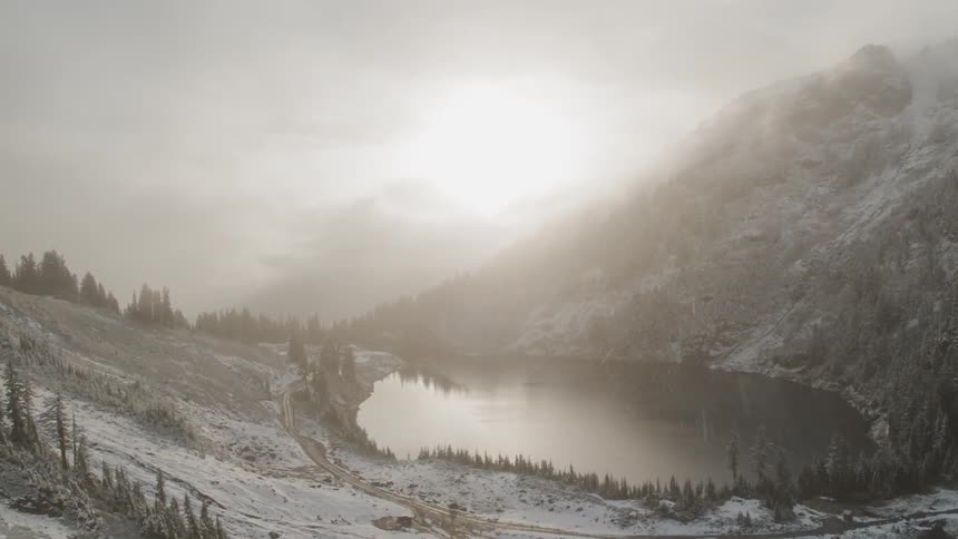 Snow falls into lake and road near mountain
