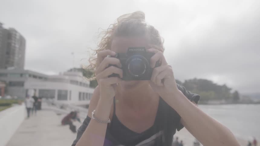 Woman takes picture on the pavement next to the beach on a cloudy day
