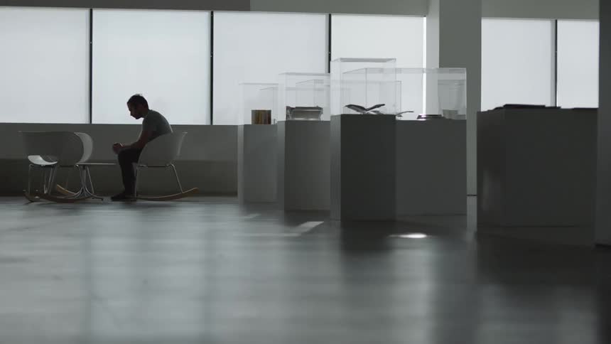 Man sits near display cases and windows