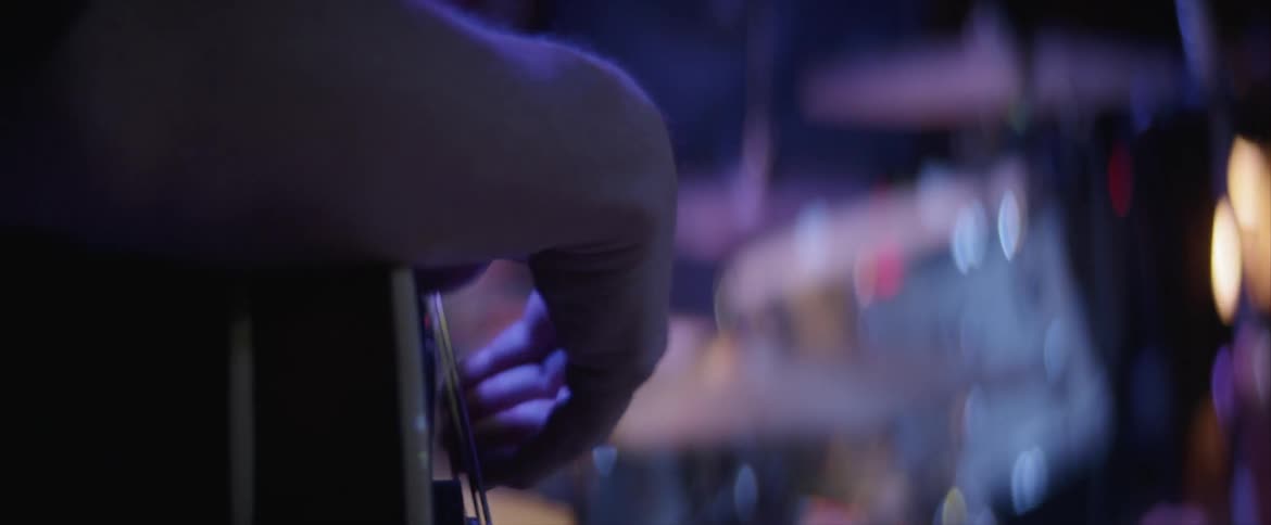 Man strums guitar on stage with band