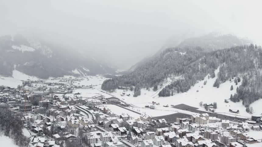 A light snow covers a small town and surrounding mountains