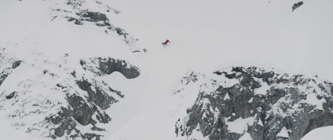 A man is snowboarding down a hill