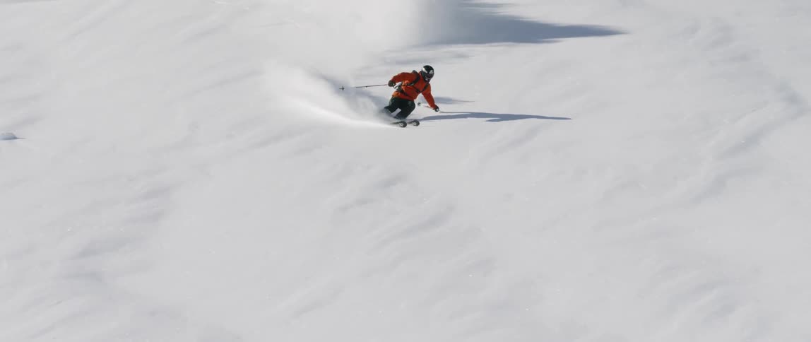 A skier jumps and spins while gliding down a snowy mountainside