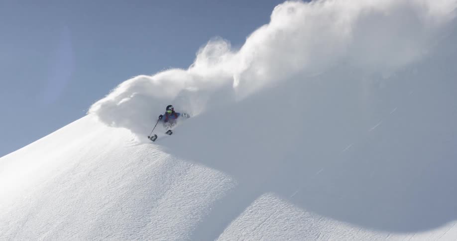 A skier skiing down a steep snow covered mountain