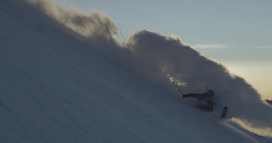 Snow flies as a skier goes down a snow covered hill