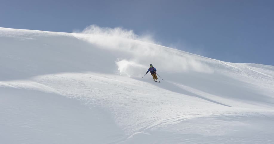 Skier skis down steep snow covered slope