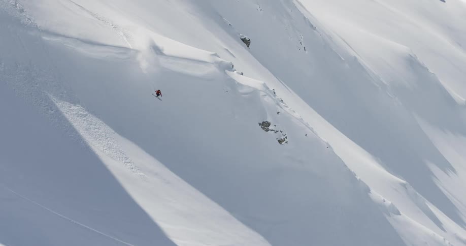A skier goes down a steep snow covered slope