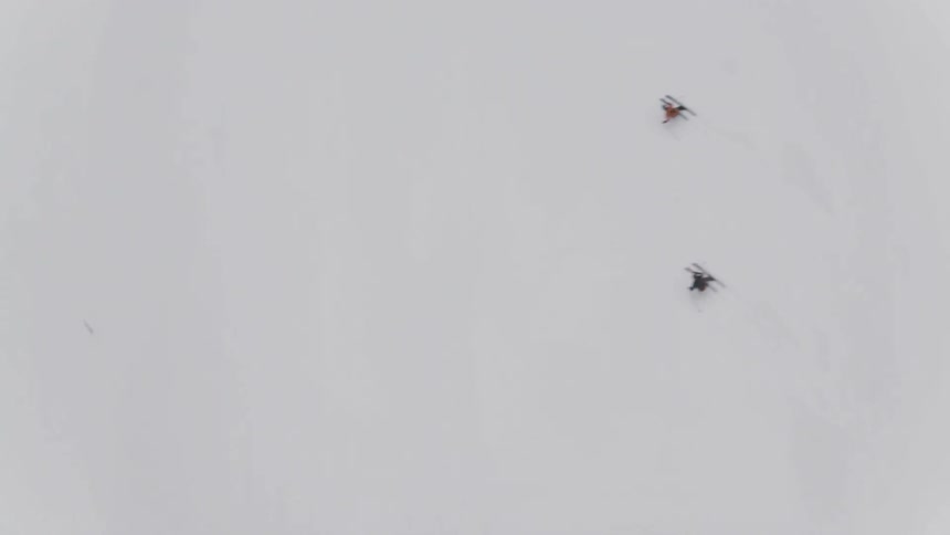 A pair of skiers zigzagging down a slope