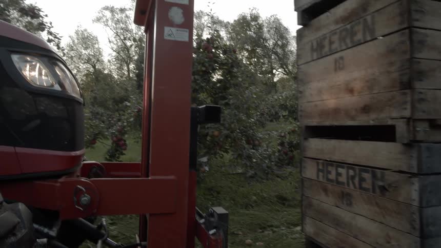 A forklift backing away from a stack of three boxes