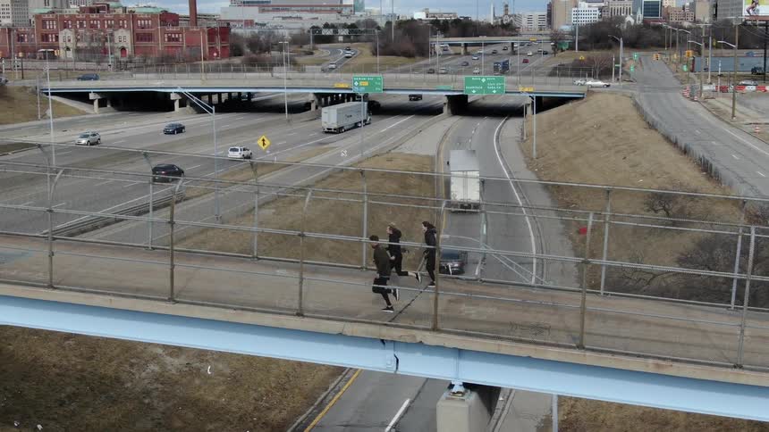 Three people run across the bridge