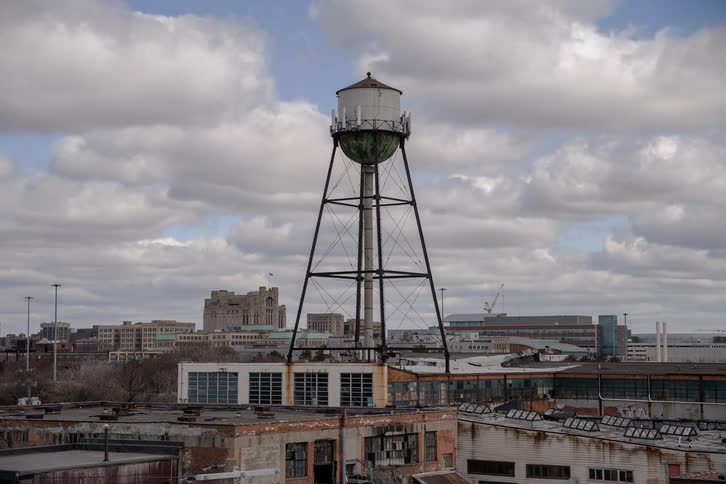 Clouds pass over an old water tower and rooftops