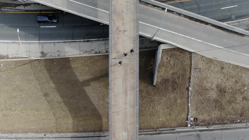 Three people run across an elevated walkway