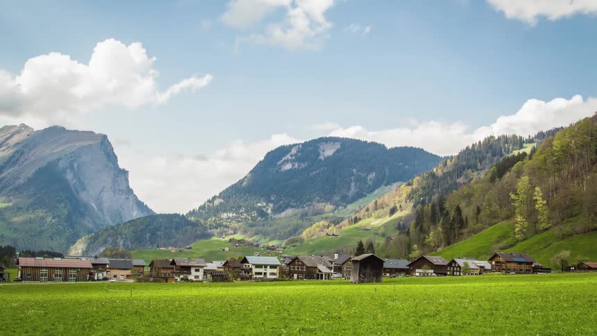 Clouds move in the sky above a rural town in a mountainous area