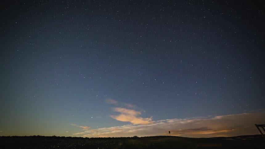 Clouds stream across sky over land and fields