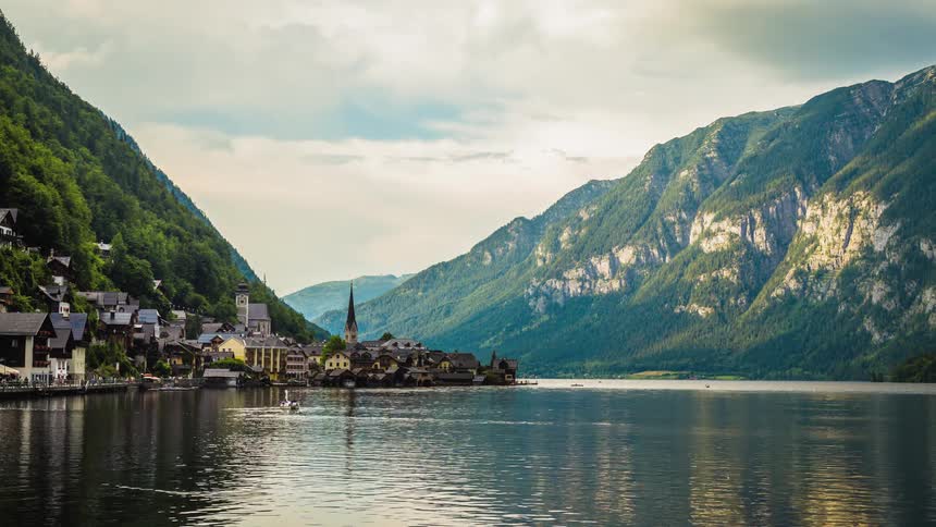 Birds swim in a lake by a mountain side town