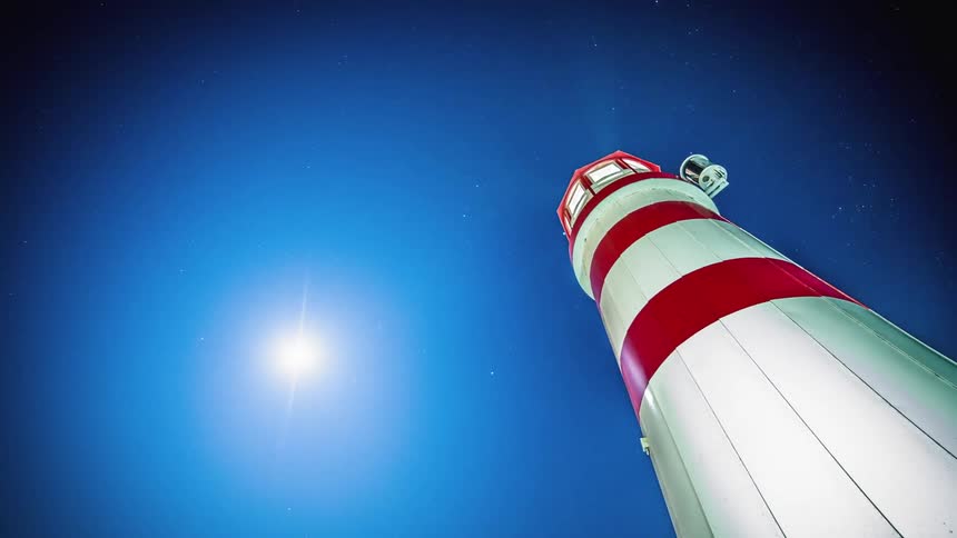 The sun sets above a lighthouse