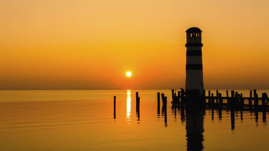 A man moves around on a pier by a lighthouse